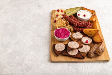 Fototapeta na wymiar set of snacks: sausages, toast, sauerkraut, marinated onion and cucumber, baked potato. Side view, copy space.