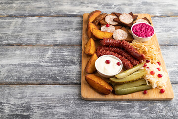 set of snacks: sausages, toast, sauerkraut, marinated onion and cucumber, baked potato. Side view, copy space.