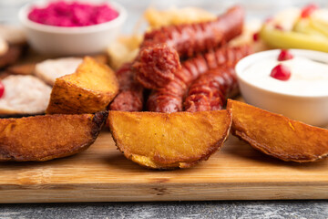 set of snacks: sausages, sauerkraut, marinated onion and cucumber, baked potato. Side view, selective focus.