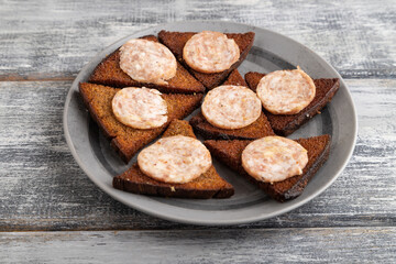 Sausage and toast on a gray wooden background. Side view, close up.