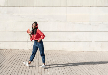 a young african american woman with braids listening to music and dancing in the street