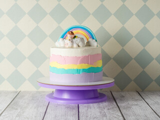 beautiful colorful children's birthday cake for a girl. cake with a rainbow, clouds and a figurine...