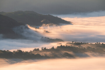 Beautiful heavenly view into British valley covered in thick fog as morning light illuminates...