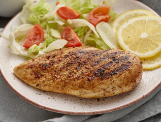 Fried chicken breast. Grilled chicken breast with vegetable salad and lemon