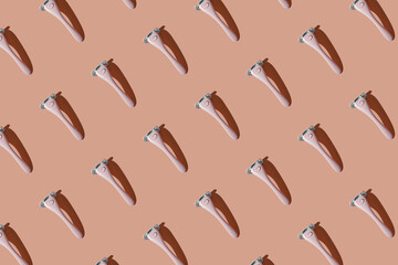 A pink women's shaving razor flat lay. Beauty hygiene routine. Body positivity movement and gender inclusiveness idea. Pink seamless pattern background.