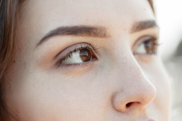 Fototapeta premium Beautiful woman with clear skin and brown eyes on a warm summer day. A woman's brown eyes