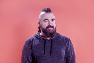 Fototapeta premium Portrait of an adult man with a mohawk and dreadlocks. A middle-aged man with a beard and an unusual hairstyle