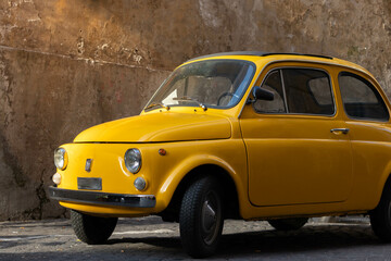 Antique vintage yellow 500 car in the streets of Trastevere in Rome, Italy - obrazy, fototapety, plakaty