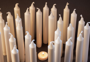 burning candle and many unlit candles