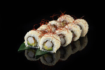 Traditional delicious fresh sushi roll set on a black background with reflection. Sushi roll with rice, nori, cream cheese, tobiko caviar, avocado. Sushi menu. Japanese kitchen. Asian food