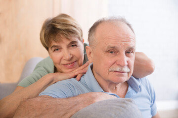 healthy seniors lifestyle. relaxing at home. portrait smiling a loving elderly couple hugs and looking at camera at home