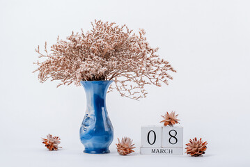 wooden calendar and a vase of flowers in the office. March 8