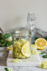 Homemade elderflower syrup with lemons and freshly picked elderflowers. The flowers are edible and can be used to add flavour and aroma to both drinks and desserts.