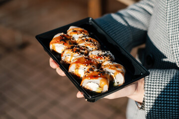 Woman holding takeaway sushi box.