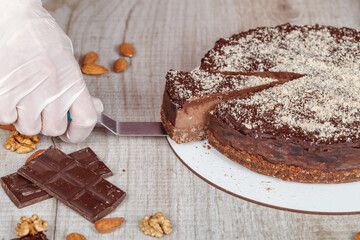 Chocolate cake with a cut piece and blade on gray background, closeup