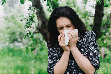A young woman with an allergy sneezing into handkerchief. Concept: Allergy season