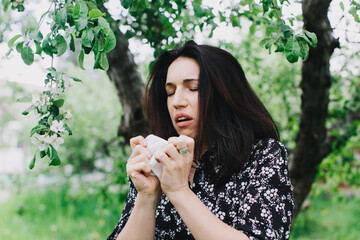 A young woman with an allergy sneezing into handkerchief. Concept: Allergy season