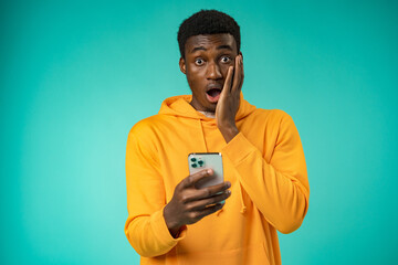 Excited black man reading good news on cellphone in studio