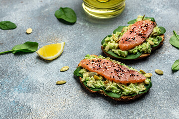 Obraz na płótnie Canvas Two toasts whole grain bread with avocado paste and salmon. keto paleo diet. Delicious breakfast or snack. Restaurant menu, dieting, cookbook recipe top view