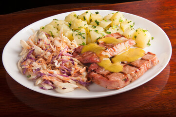 pork loin meal, coleslaw salad and boiled potatoes with green onions angle view