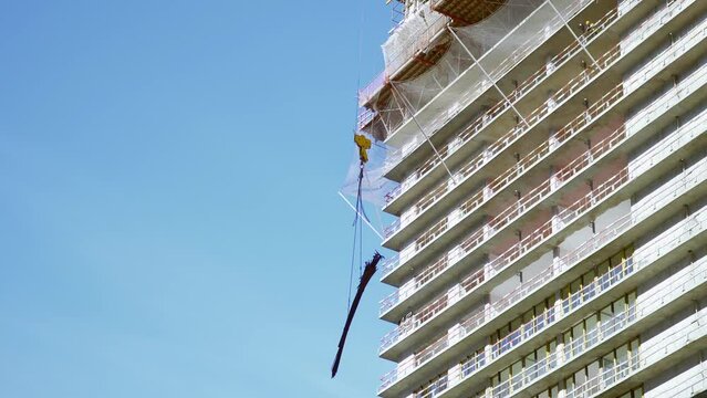 Raise building load to height. Crane lowers loads at construction site. Work process. Crane lifts materials on roof for construction decoration. raised telescopic boom on site. sling hoist crane arm