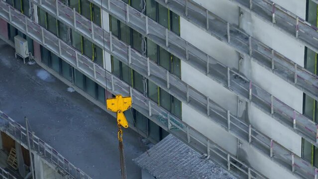 Raise building load to height. Crane lowers loads at construction site. Work process. Crane lifts materials on roof for construction decoration. raised telescopic boom on site. sling hoist crane arm