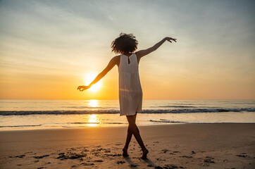 Young Afro American girl dancing barefoot on beach