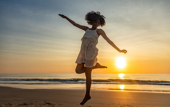 Barefoot young African American woman dancing on beach