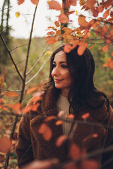 View of a brown woman through branches and leaves in a forest.