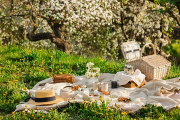 Breakfast picnic with waffles and tea in spring blossom garden on a white tablecloth on a sunny...