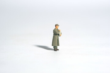 Miniature people toy figure photography. A military mail officer holding news pack. Isolated on white background