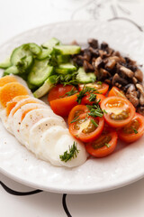 Closeup of chopped eggs, fried eggplants and organic garden vegetables on a white plate: tomatoes, cucumbers and dill. Healthy nutrition. Cook at home.