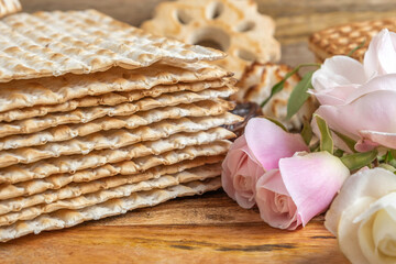Pink roses on the background of traditional food for Jewish holiday Pesach matzah.