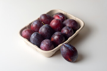 Organic sugar plums in ecological paper tray on light background.