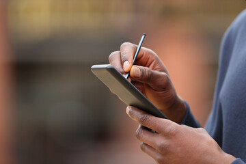 Man with black skin hands using pen on phone