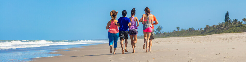 Panoramic view of friends jogging together on beach