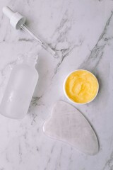 Guasha and cream textures on the marble surface