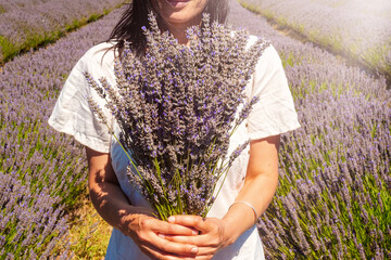 Woman holding a bunch of lavender in the middle of a lavender farm.
