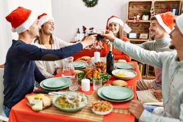 Group of young people smiling happy celebrating christmas toasting with wine at home.