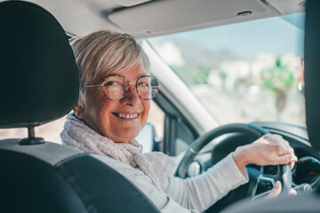 Happy owner. Handsome mature woman sitting relaxed in his newly bought car looking at the camera smiling joyfully. One old senior driving and having fun..