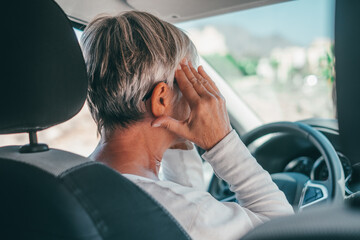 One senior or mature female people having and feeling bad headache in car while driving. Feeling pain while driving on road - obrazy, fototapety, plakaty