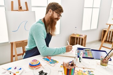 Young redhead man smiling confident drawing on notebook at art studio