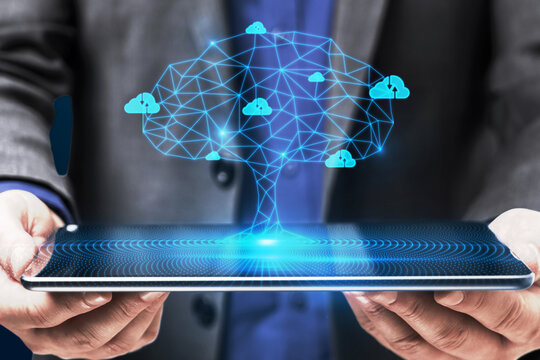 Close up of businessman hand holding tablet with abstract digital polygonal cloud tree on blue background. Computer, data and security concept. - Powered by Adobe