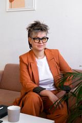 fashion business woman queer portrait, sitting on couch at modern workplace