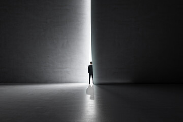 Back view of businessman stepping into the light from behind a concrete wall. Success and future...