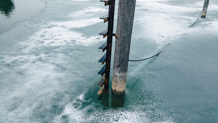 Ladder on a pole into the frozen pond - Powered by Adobe