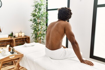 Young african american man sitting on massage board at beauty center