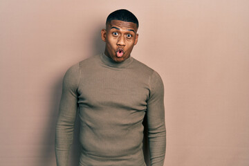 Young black man wearing casual turtleneck sweater afraid and shocked with surprise expression, fear and excited face.