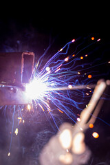 welder working on a metal structure fixing an urgent problem on the night shift close-up, front and back background blurred with bokeh effect