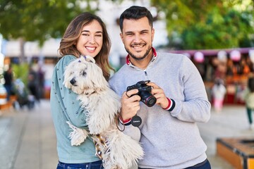 Man and woman holding dog using professional camera at park